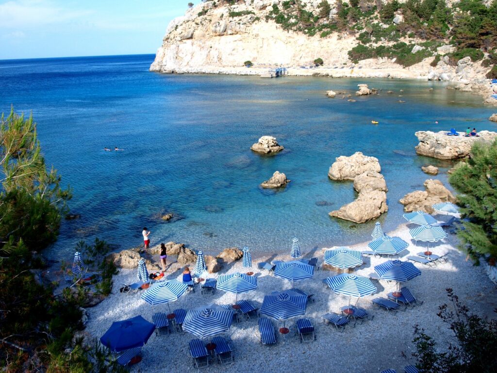 Sunbeds and clear turquoise water at Anthony Quinn Bay
